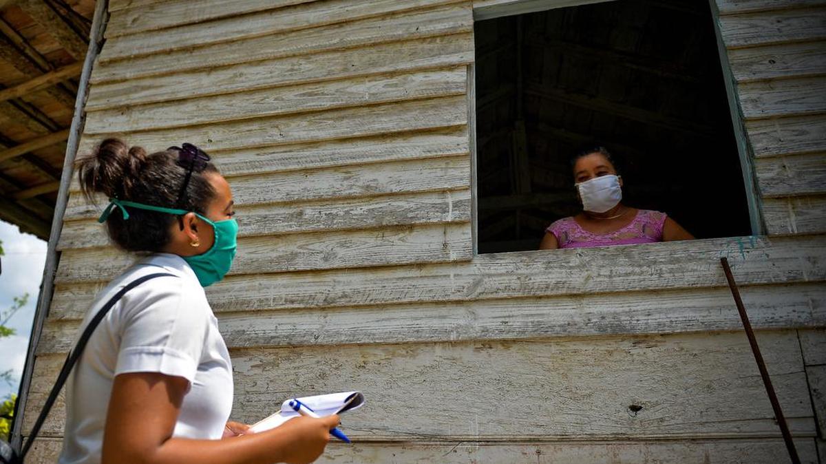 La estudiante de medicina cubana Darlyn de la Caridad habla con una mujer en busca de posibles casos del nuevo coronavirus, COVID-19, en Zaragoza, provincia de Mayabeque, Cuba, el 28 de abril de 2020. 