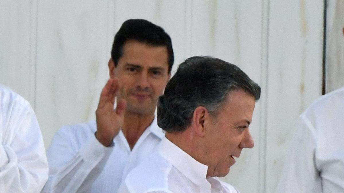 El momento en que el presidente de Colombia, Juan Manuel Santos, y el comandante Rodrigo Londoño, alias "Timochenko", se saludan después de firmar el acuerdo de paz el lunes 26 de septiembre de 2016, en Cartagena, Colombia.  