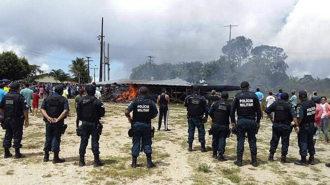 Policías brasileños vigilan mientras ciudadanos brasileños protestan contra la presencia de inmigrantes venezolanos el sábado 18 de agosto de 2018, en la localidad fronteriza de Pacaraima, Brasil. GERALDO MAIA. EFE