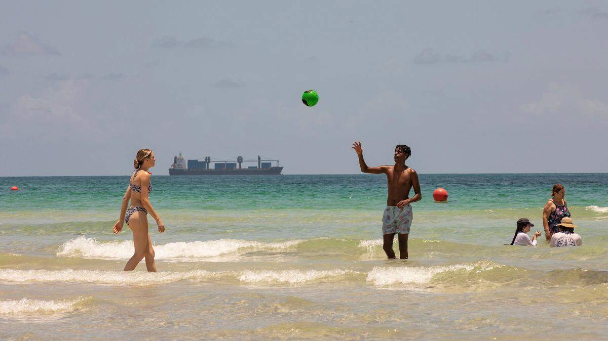 Kellsie Collins (left) and Nati Collins (right) of St. Louis, MO are seen playing catch while on vacation in the water in Miami Beach, Fla. on Monday, Jun. 13, 2022. In Miami-Dade County, a high of 91 is expected-- although the heat index could reach 102 degrees in some areas, according to the National Weather Service.