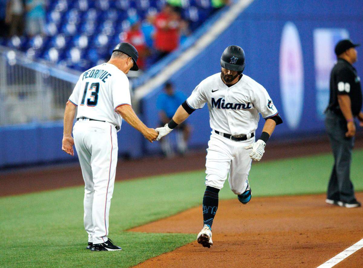 El antesalista de los Marlins Jon Berti es felicitado por el coach de tercera base Al Pedrique tras pegar un jonrón en el primer inning del partido ante los Diamondback de Arizona, celebrado el 4 de mayo de 2022 en Miami.