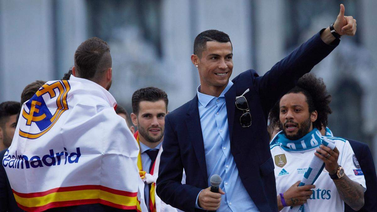 Cristiano Ronaldo (centro) habla en Madrid tras el título del equipo blanco en la Liga de Campeones el 27 de mayo de 2018. El brasileño Marcelo (der.) participa en la celebración.