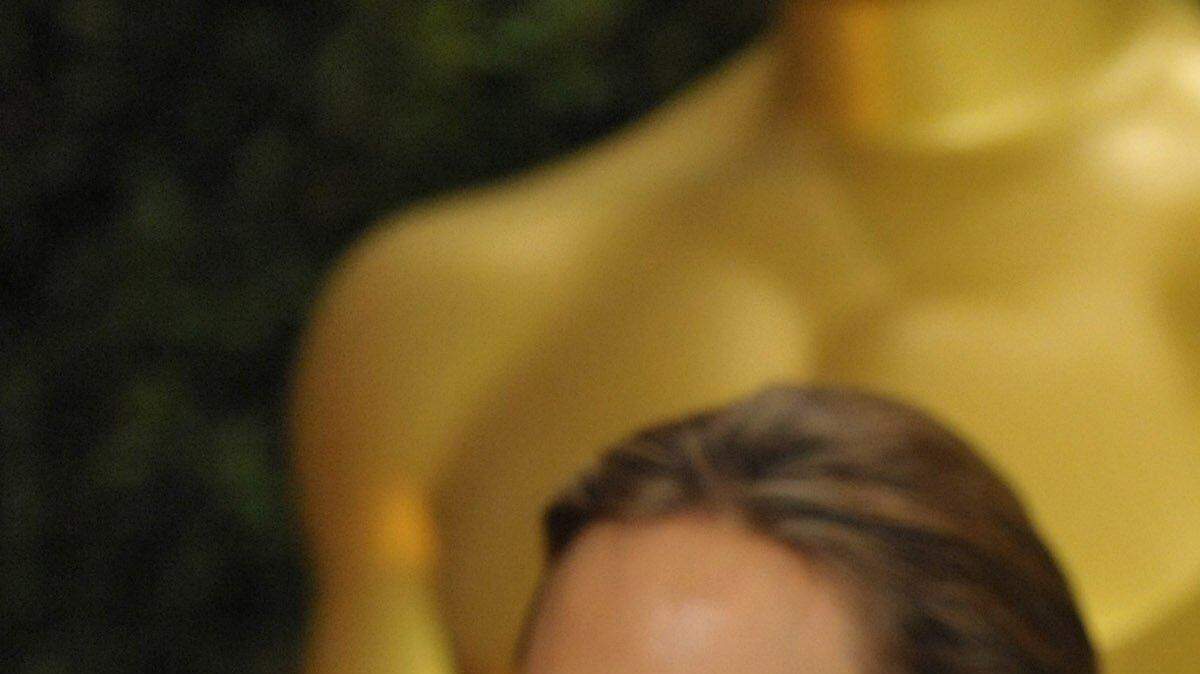 El actor Brad Pitt con su hijo de 15 años, Maddox, en la alfombra de los Premios de Gobernadores 2013 en Los Ángeles. Angelina Jolie al fondo.