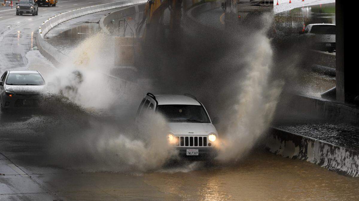 Vehículos salpican una leve inundación en los carriles en dirección norte de la autopista 101 en California Street en Ventura cuando la dirección sur se fusiona en un solo carril después de que la lluvia cayera temprano en el condado de Ventura.