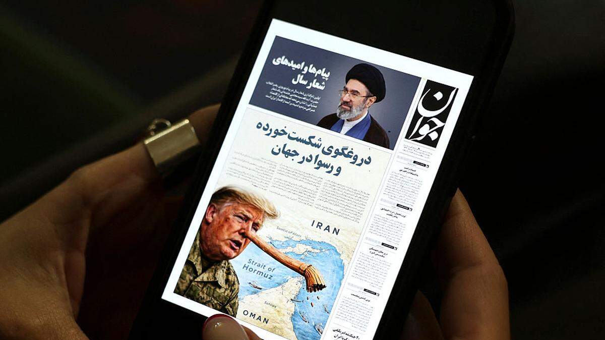 Una mujer iraní lee una edición digital del periódico *Javan* en su teléfono móvil en Teherán, el miércoles 25 de marzo de 2026. El miércoles, los periódicos iraníes ridiculizaron lo que calificaron como las “mentiras” de Donald Trump respecto a las conversaciones diplomáticas en curso para poner fin a la guerra, publicando caricaturas del presidente estadounidense representado como Pinocho.