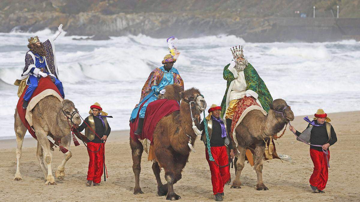 Los Reyes Magos a su llegada hoy en camello a una playa del norte de España.