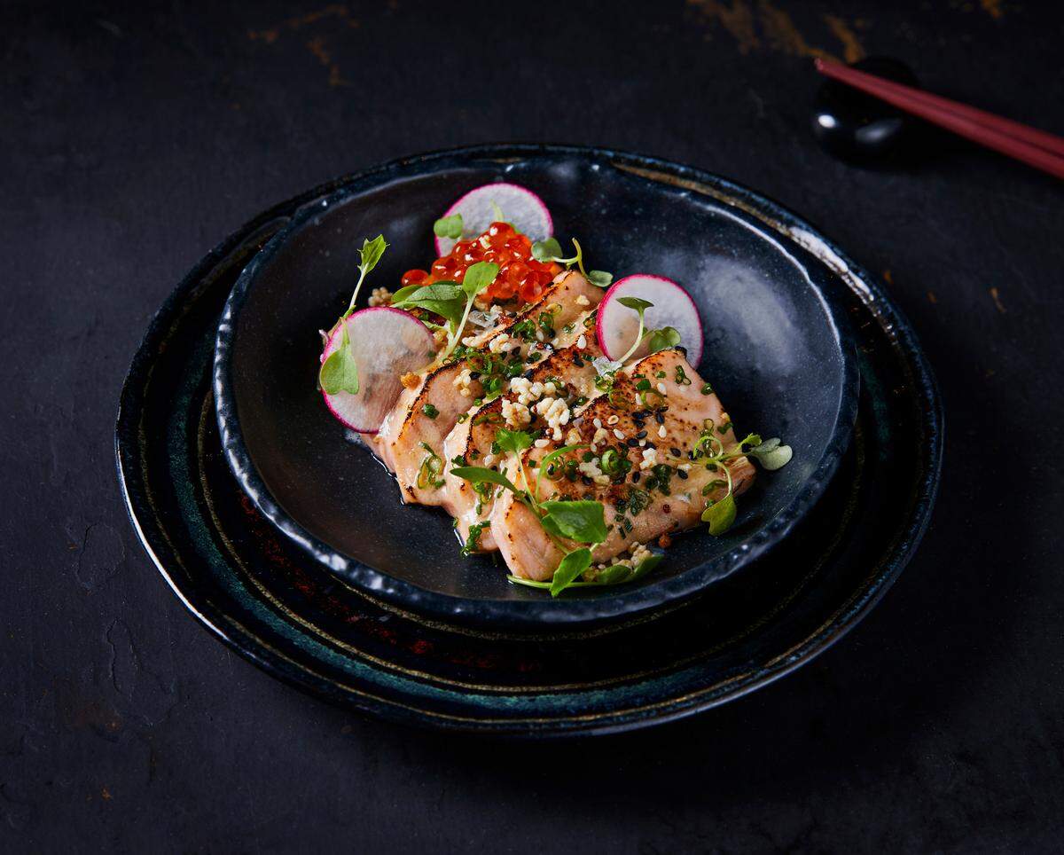 Salmón sashimi, con glaseado de miso y rodajas de rábanos, Ikura o caviar rojo, con quinua crujiente y hierbas frescas.