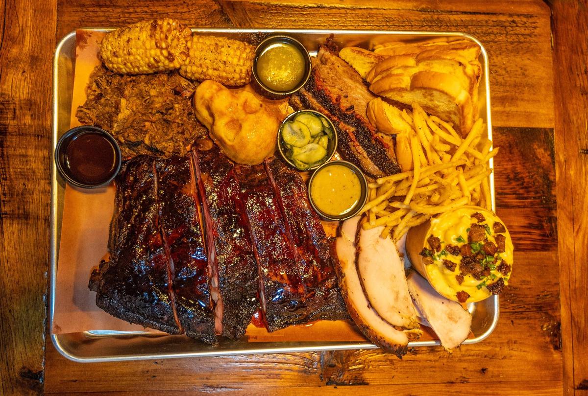 Un pedido de costillas de cerdo, cerdo desmenuzado, pechuga de res, pavo ahumado, macarrones con queso, maíz frito, pan de maíz (en forma de calavera) y papas fritas de Apocalypse BBQ.