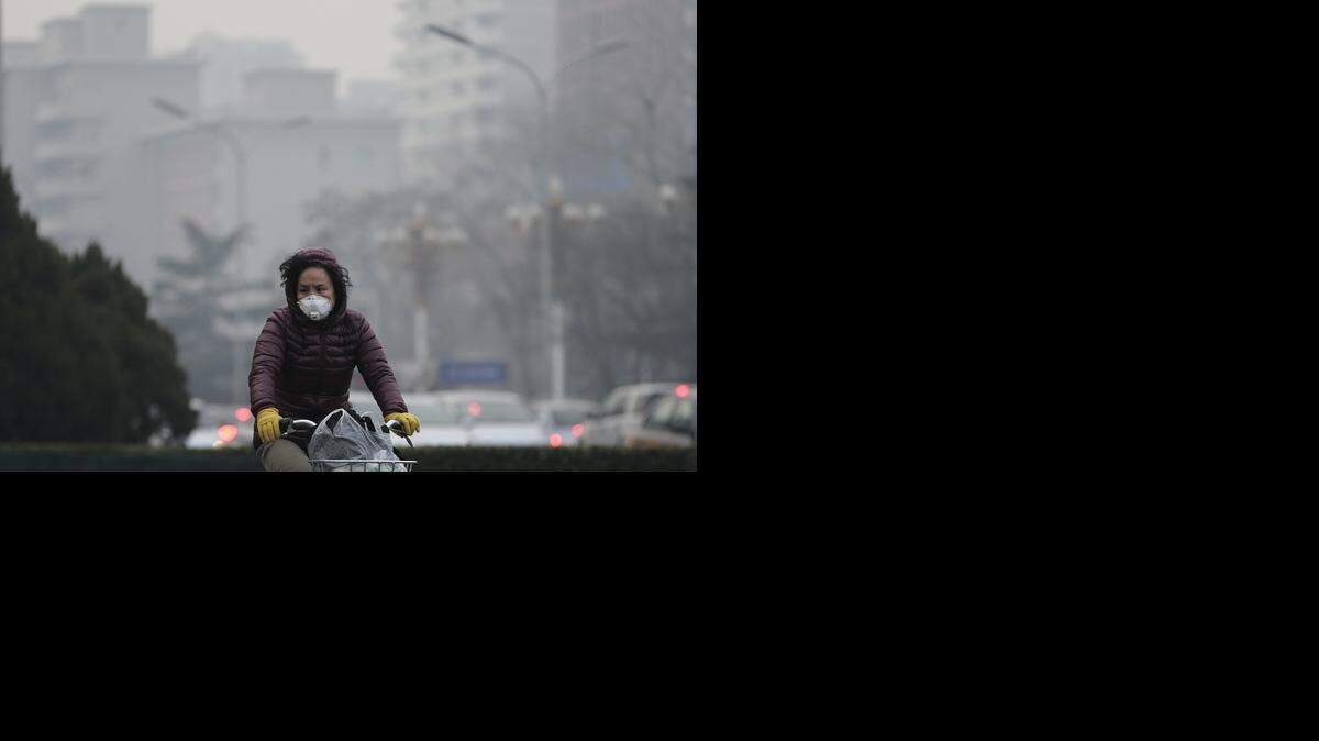 Una mujer lleva una máscara mientras monta bicicleta en una carretera de Beijing, el domingo, 13 de de diciembre de 2015. AP-Archivo