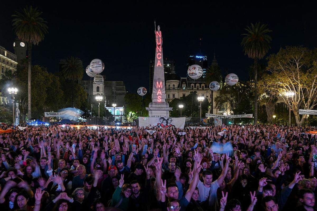 La gente se congrega en la Plaza de Mayo, en Buenos Aires, el 23 de marzo de 2026 —con la Pirámide de Mayo iluminada con la frase “Nunca más” de fondo— para asistir a una vigilia, un día antes del 50.º aniversario del golpe militar que dio inicio a la dictadura militar (1976-1983).