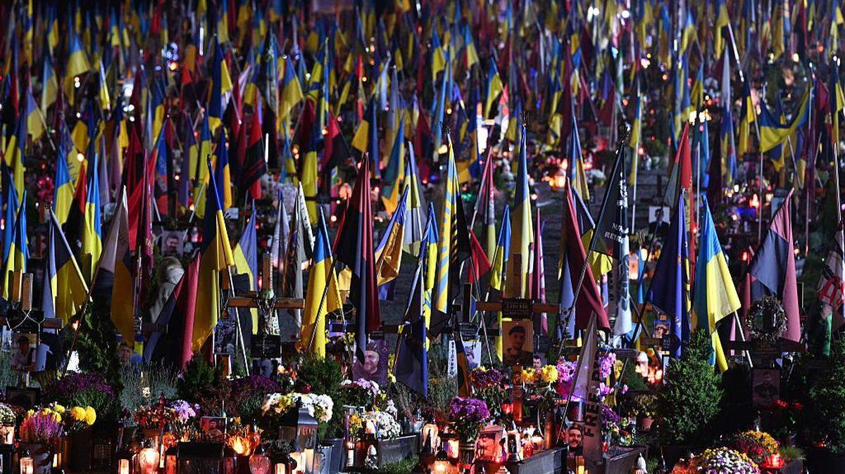 This photograph shows the graves of fallen Ukrainian soldiers surrounded by lit candles and Ukrainian national flags on the eve of All Saints' Day at Lychakiv Cemetery in Lviv on October 31, 2025, amid the Russian invasion of Ukraine. (Photo by YURIY DYACHYSHYN / AFP) (Photo by YURIY DYACHYSHYN/AFP via Getty Images)
