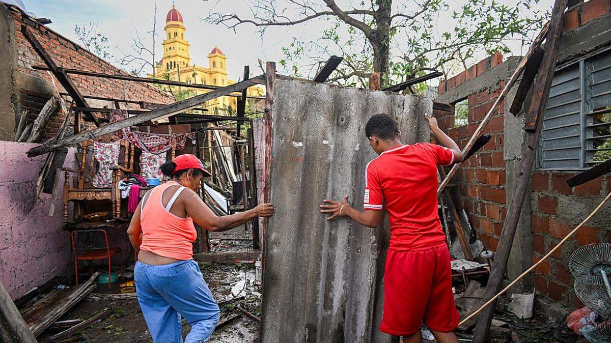 Residents of El Cobre, in the province of Santiago de Cuba, recover parts of their damaged house after the passage of Hurricane Melissa, on October 29, 2025. Hurricane Melissa was moving towards Bermuda on Thursday after ripping a path of destruction through the Caribbean that left at least 20 people dead in Haiti, and parts of Jamaica and Cuba in ruins. (Photo by YAMIL LAGE / AFP) (Photo by YAMIL LAGE/AFP via Getty Images)