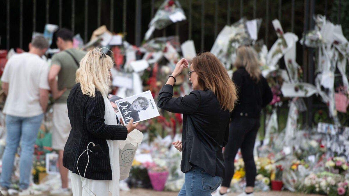 Los fanáticos de Alain Delon se toman una foto frente a una de las entradas cubiertas de flores de su finca, en Douchy, Francia, el 23 de agosto de 2024. 