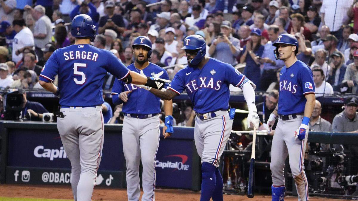 El torpedero de los Rangers de Texas Corey Seager recibe la felicitación del cubano Adolis García tras pegar un jonrón en el tercer inning ante los Diamondbacks, en el tercer partido de la Serie Mundial celebrado el 30 de octubre de 2023 en Phoenix, Arizona.