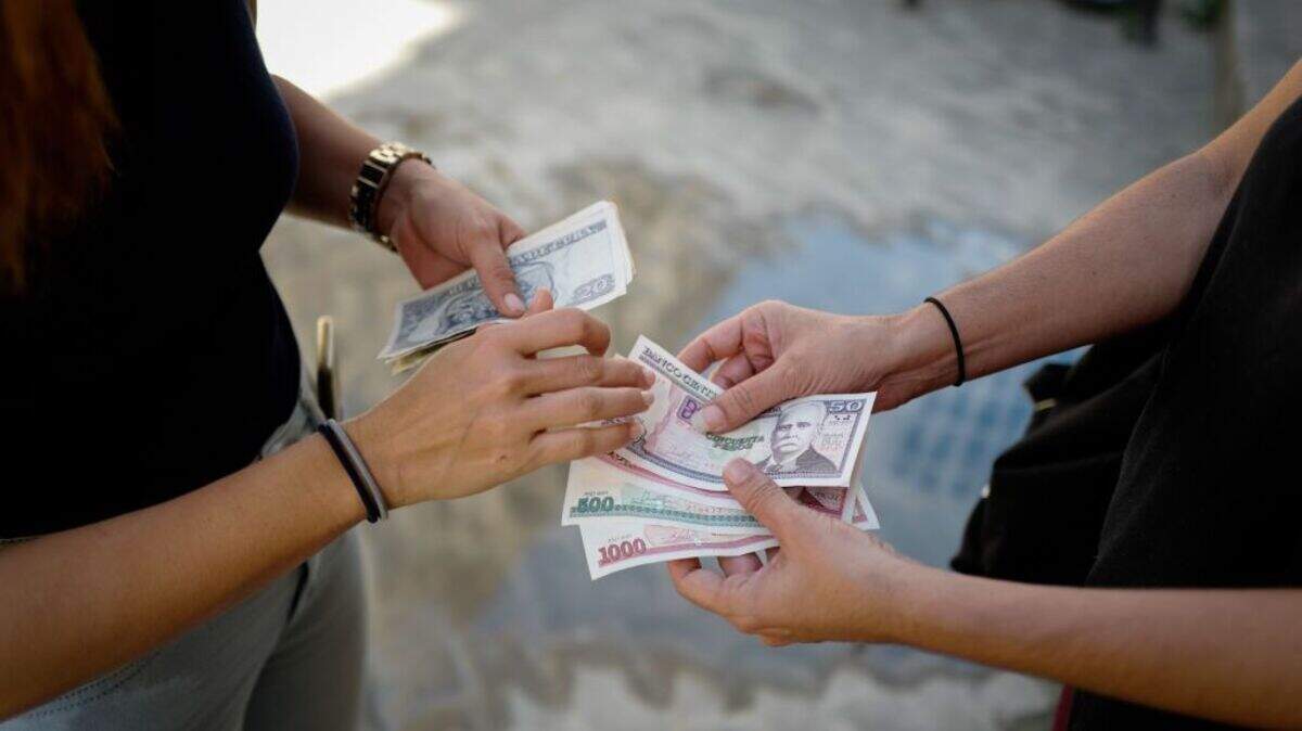 Foto de archivo de personas revisando billetes de pesos cubanos de diversas denominaciones frente a una oficina de cambio en La Habana,  Cuba, el 15 de diciembre de 2020.