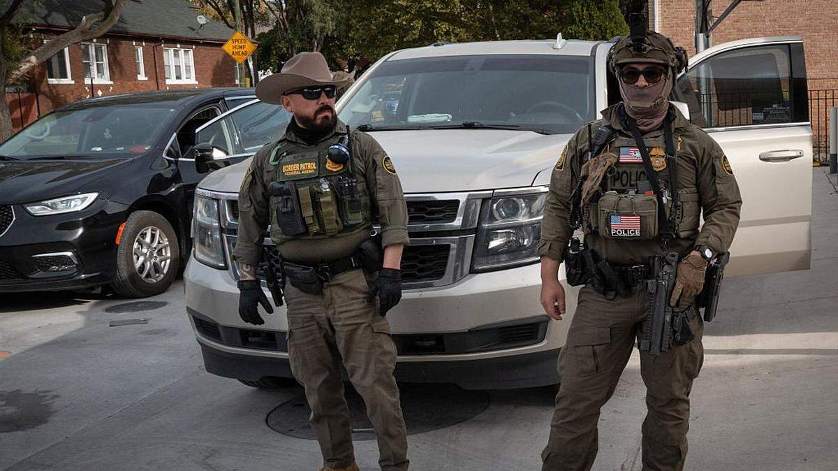 CHICAGO, ILLINOIS - NOVEMBER 06: Federal agents stand guard as they are confronted by residents after making a stop while driving in a caravan through the Brighton Park neighborhood on November 06, 2025 in Chicago, Illinois. Federal agents participating in Operation Midway Blitz, engage in daily patrols through Chicago neighborhoods and surrounding suburbs searching for undocumented immigrants. (Photo by Scott Olson/Getty Images)