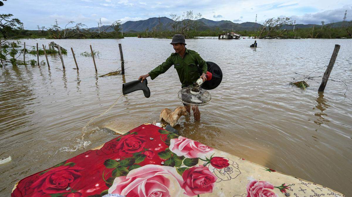 A farmer rescues his dog and some belongings from his flooded house after Hurricane Melissa passed through the town of San Miguel de Parada in Santiago de Cuba province on October 29, 2025. A powerful Hurricane Melissa made landfall in eastern Cuba on Wednesday, causing damage and flooding to homes and streets in Santiago de Cuba province, an AFP team on the ground reported. (Photo by YAMIL LAGE / AFP) (Photo by YAMIL LAGE/AFP via Getty Images)
