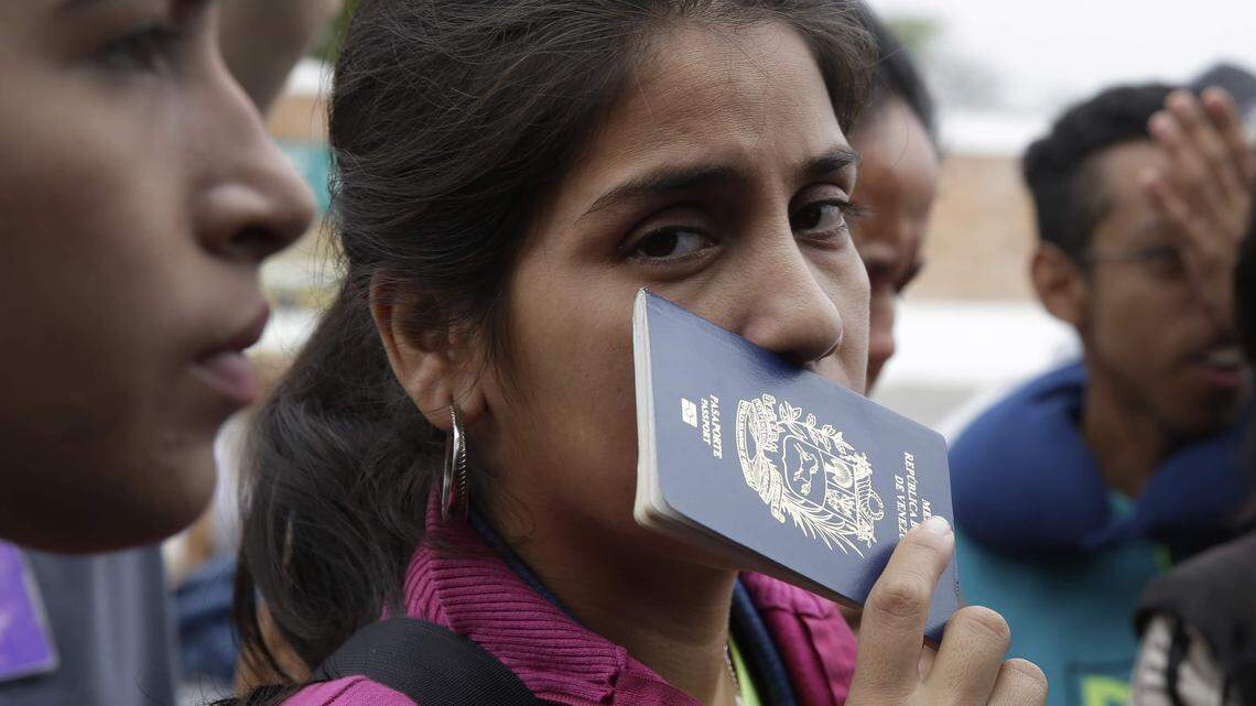 Foto de archivo. Una emigrante venezolana sostiene su pasaporte mientras espera en una fila para tomar un autobus en Tumbes, Perú.