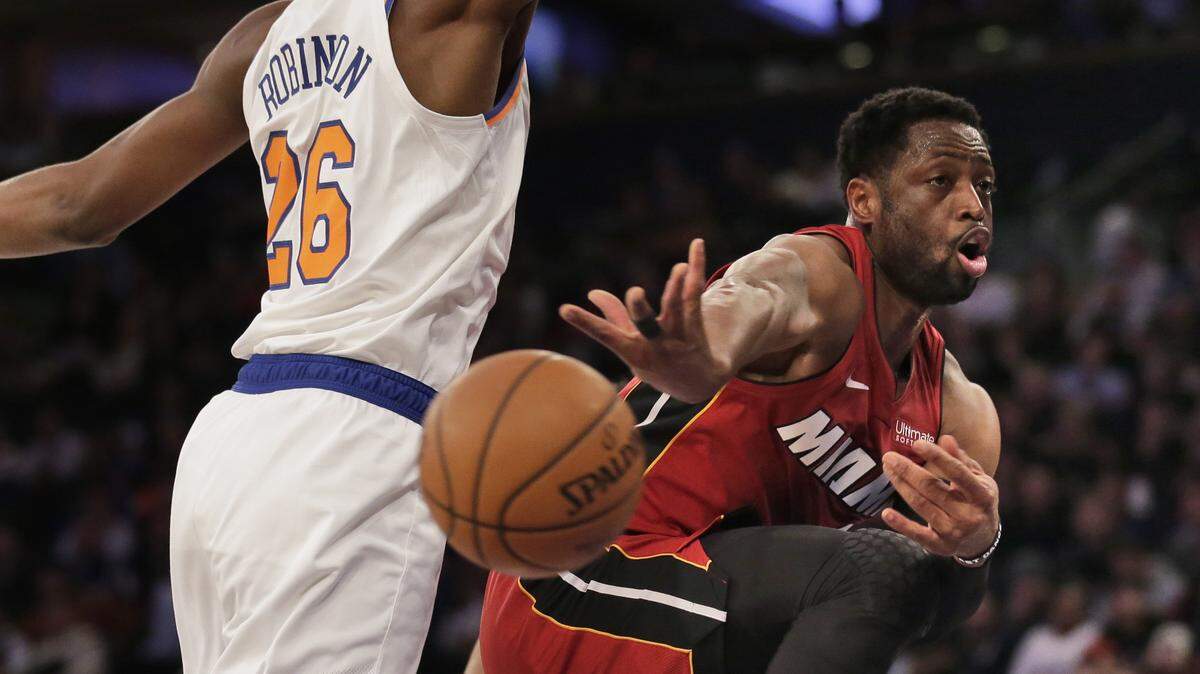 El jugador del Heat Dwyane Wade (der.) pasa la bola ante la marca de Mitchell Robinson, de los Knicks, en el partido efectuado el 27 de enero de 2019 en Nueva York.