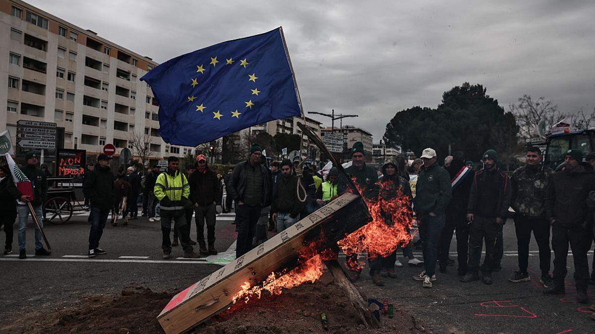 Una bandera de la Unión Europea se ve sobre un ataúd falso en llamas durante una protesta que forma parte de un movimiento nacional contra el acuerdo comercial entre la UE y Mercosur en Aix-en-Provence, en el sur de Francia, el jueves 16 de enero de 2026.