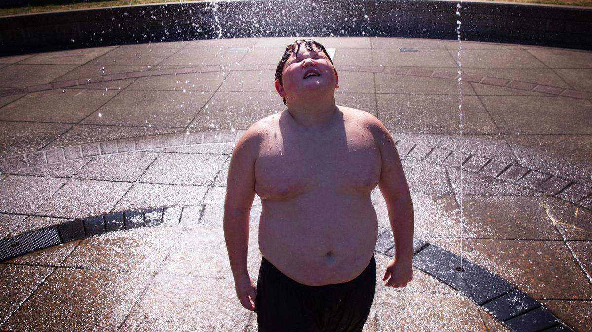 Parker Hesgard, de 9 años, se refresca en una fuente frente al Ayuntamiento de Eugene, Oregon, el martes 2 de julio de 2024.