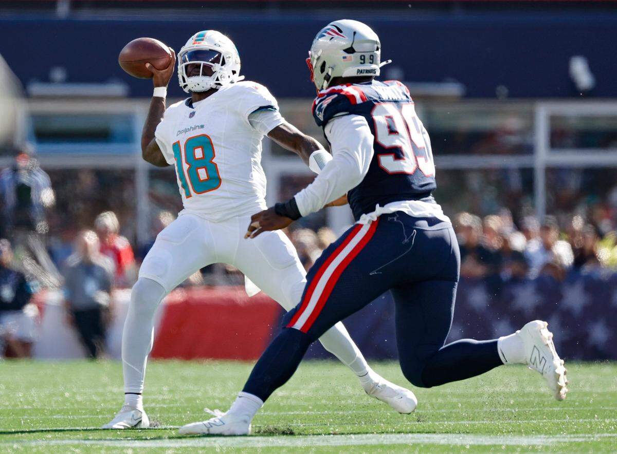 El quarterback de los Dolphins de Miami Tyler Huntley (izq.) trata de pasar el ovoide ante la marca del defensive end de los Patriots Keion White, en el partido de la NFL celebrado el 6 de octubre de 2024 en el Gillette Stadium en Foxborough, Massachusetts.
