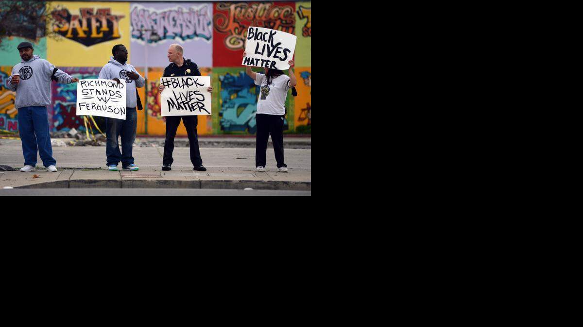 
Varias personas, entre ellas el jefe de policía de la localidad californiana de Richmond (segundo desde la derecha), protestan contra la muerte de afroamericanos a manos de agentes.
