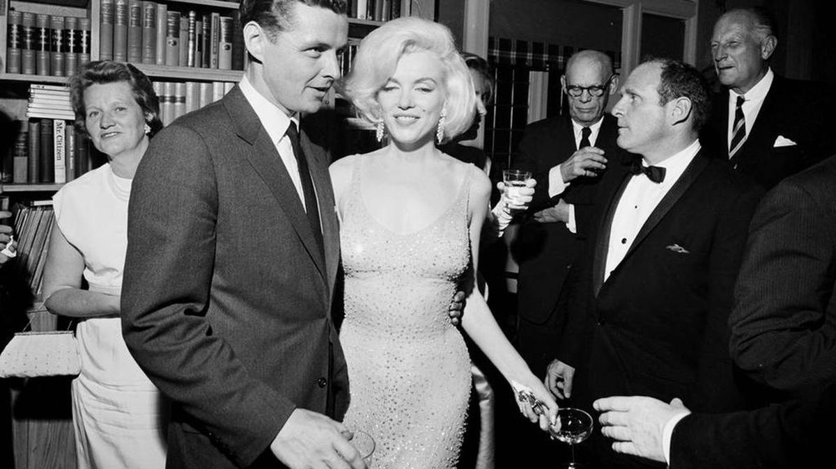 Foto del 19 de mayo de 1962 de la actriz Marilyn Monroe con el icónico vestido que usó mientras cantaba "Feliz Cumpleaños" al Presidente John F. Kennedy en el Madison Square Garden. Al lado de Monroe está Steve Smith, cuñado del presidente Kennedy.