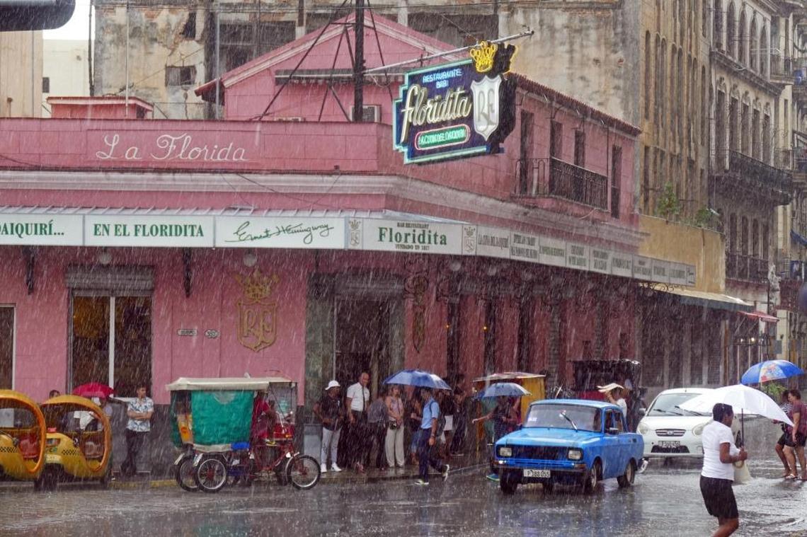 Tourists and locals try to keep dry under the awning of the Floridita in Old Havana during a downpour.