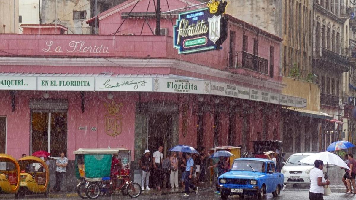 Varios turistas se guarecen de la lluvia bajo un toldo del bar El Floridita, en la Habana Vieja.