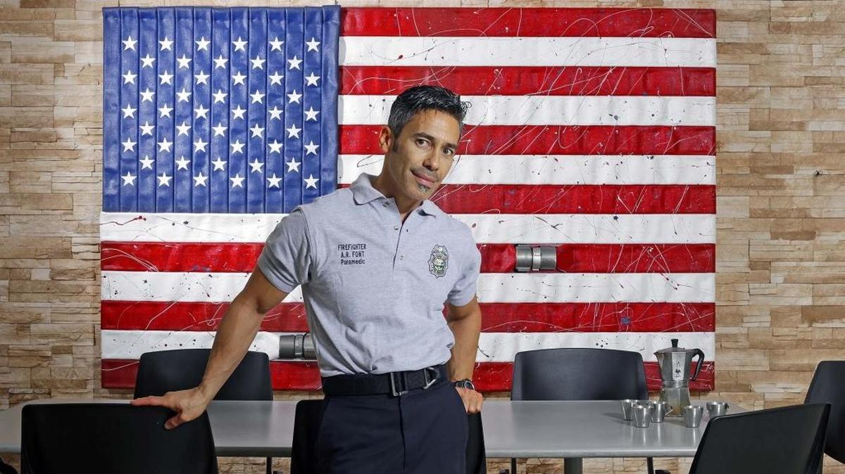 El bombero Axel Font junto a la bandera norteamericana que hizo con mangueras en la estación número 40 de Miami-Dade.