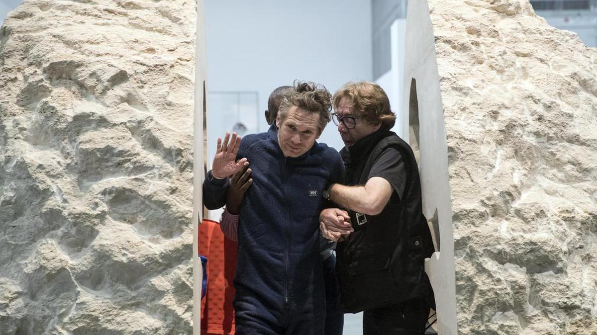 El artista galo Abraham Poincheval (i) es ayudado a salir de una roca de 12 toneladas como parte de su performance "Pierre", en el Palais de Tokyo de París, Francia, e1 de marzo de 2017.