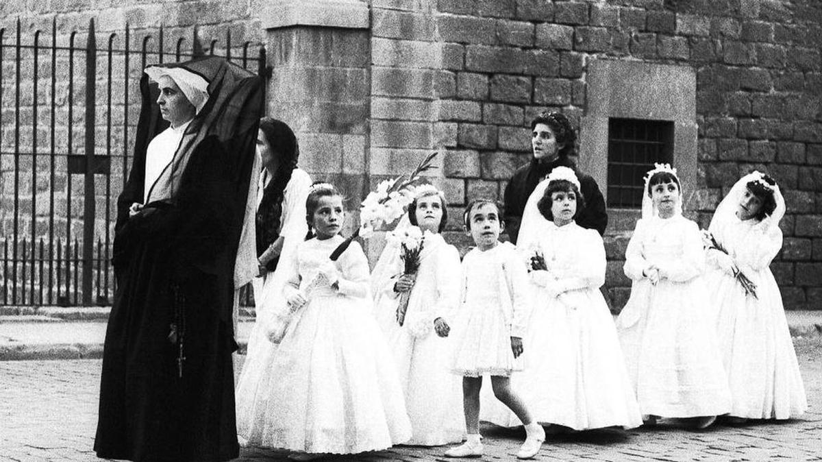 La imagen de un coro de niñas salidas del colegio Inmaculada Concepción, guiadas por una monja felliniana, una de las fotografías más logradas de esta colección