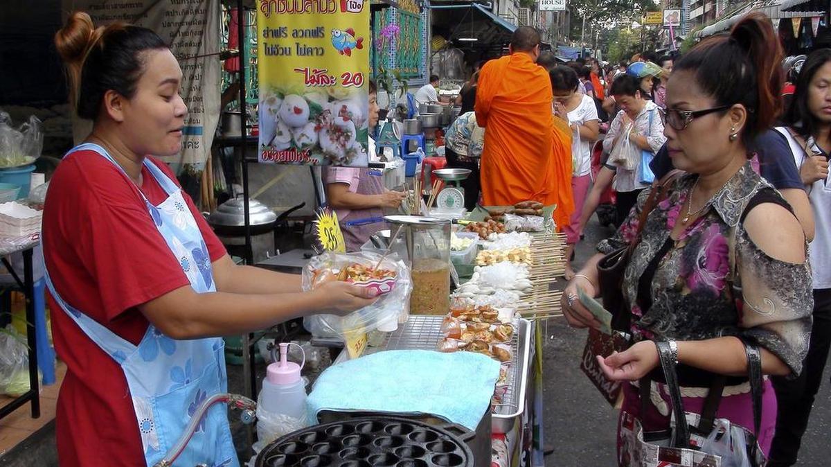 Una vendedora ambulante conversa con una clienta en el mercado callejero Wat Khek Soi 20 de Silom en Bangkok. El gusto por la comida callejera, que se está convirtiendo en tendencia internacional a pasos de gigante, es una de la tradiciones más arraigadas de Bangkok, donde proliferan los puestos gastronómicos en las aceras.