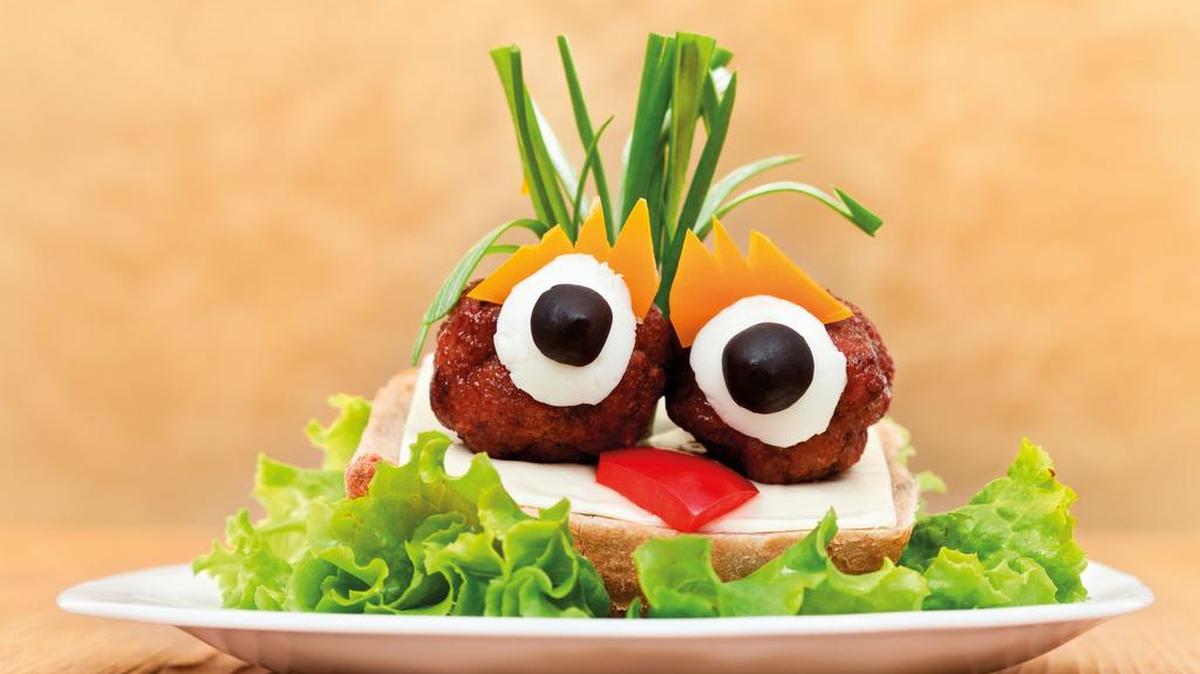 
Albóndigas sobre sándwich de queso con ensalada.
