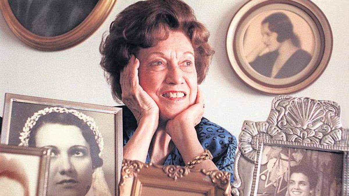 Elena Ruth en su apartamento cuando vivía en Kendall. Tras ella fotos que la muestran durante su juventud en Cuba.