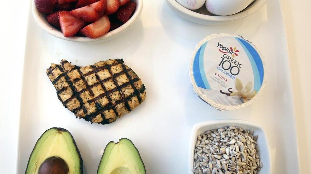Gina Sweat, dietista de Cleveland Clinic Florida, explica que las necesidades dietéticas de las mujeres cambian con la edad. Entre los alimentos saludables recomendados para las mujeres están, de izquierda a derecha comenzando por arriba: fresas, huevos, yogur, semillas de girasol, aguacate y pechuga de pollo a la parrilla.