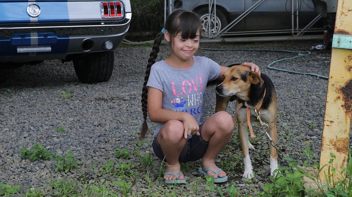 Una niña con síndrome de down juega con su perro en Puerto Rico, el 11 de agosto del 2018.
