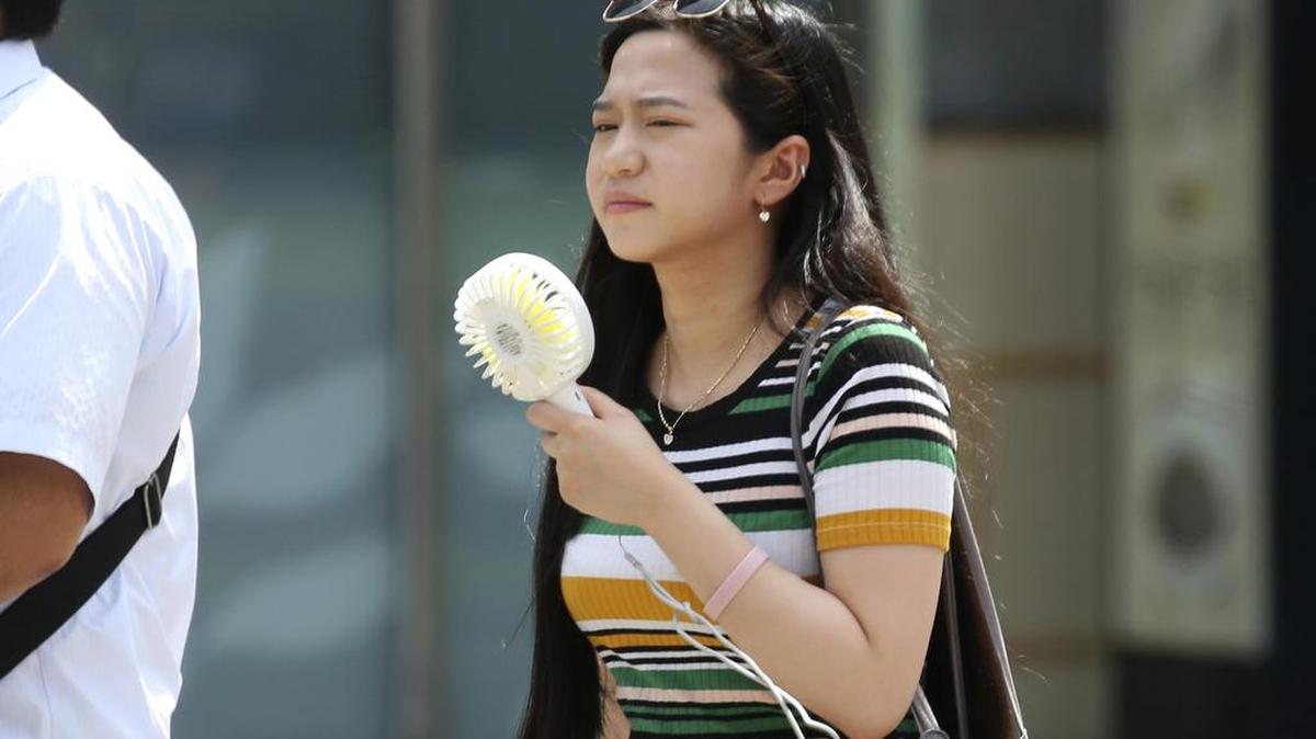 Una mujer sostiene un ventilador portátil en un distrito comercial en Tokio, el lunes 23 de julio de 2018. 