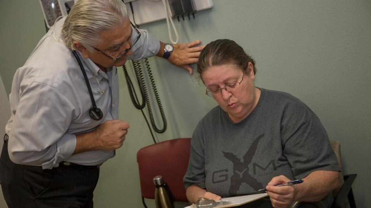 El doctor Ronald Cirillo ayuda a Deborah Hatfield a llenar formularios en la clínica de Florida Turning Points, antes de hacerle la prueba para saber si tiene hepatitis C.