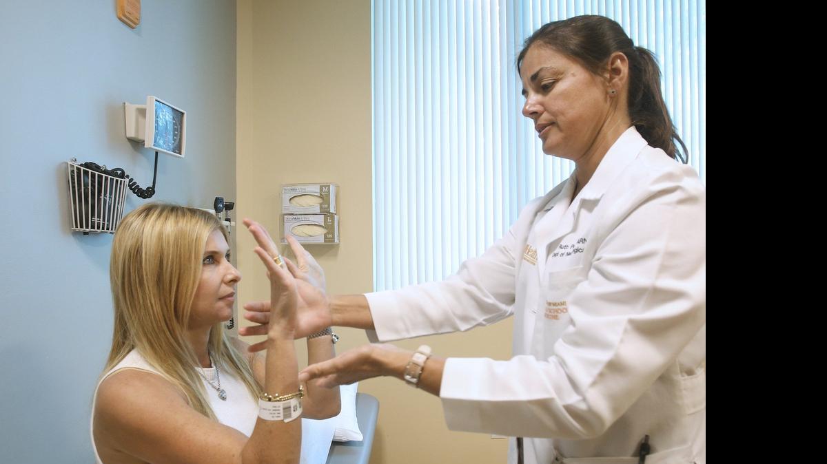 
La enfermera Ruth Pérez (dcha), de la University of Miami Miller School of Medicine Spine Institute, realiza un examen neurológico a Lily Rubin, quien sufre de migrañas.


