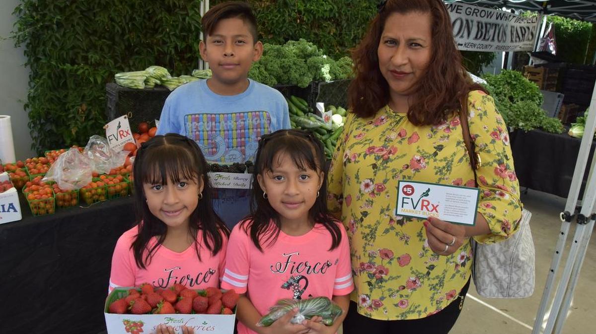 Una fotografía del 27 de julio de 2017 muestra a María Cornelio (d), beneficiaria del programa de Frutas y Verduras con receta médica (FVRx), asistiento con sus hijos al mercado de pequeños agricultores, de donde llevan fresas y moras para balancear su alimentación, en el sur de Los Ángeles, California.
