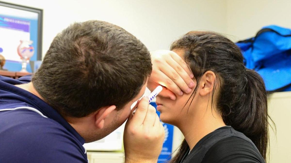 Danielle Guillama, de 16 años, es examinada para ver alguna señal de conmoción cerebral después de haberse golpeado en la cabeza durante un juego de basketball en Miami Palmetto High.