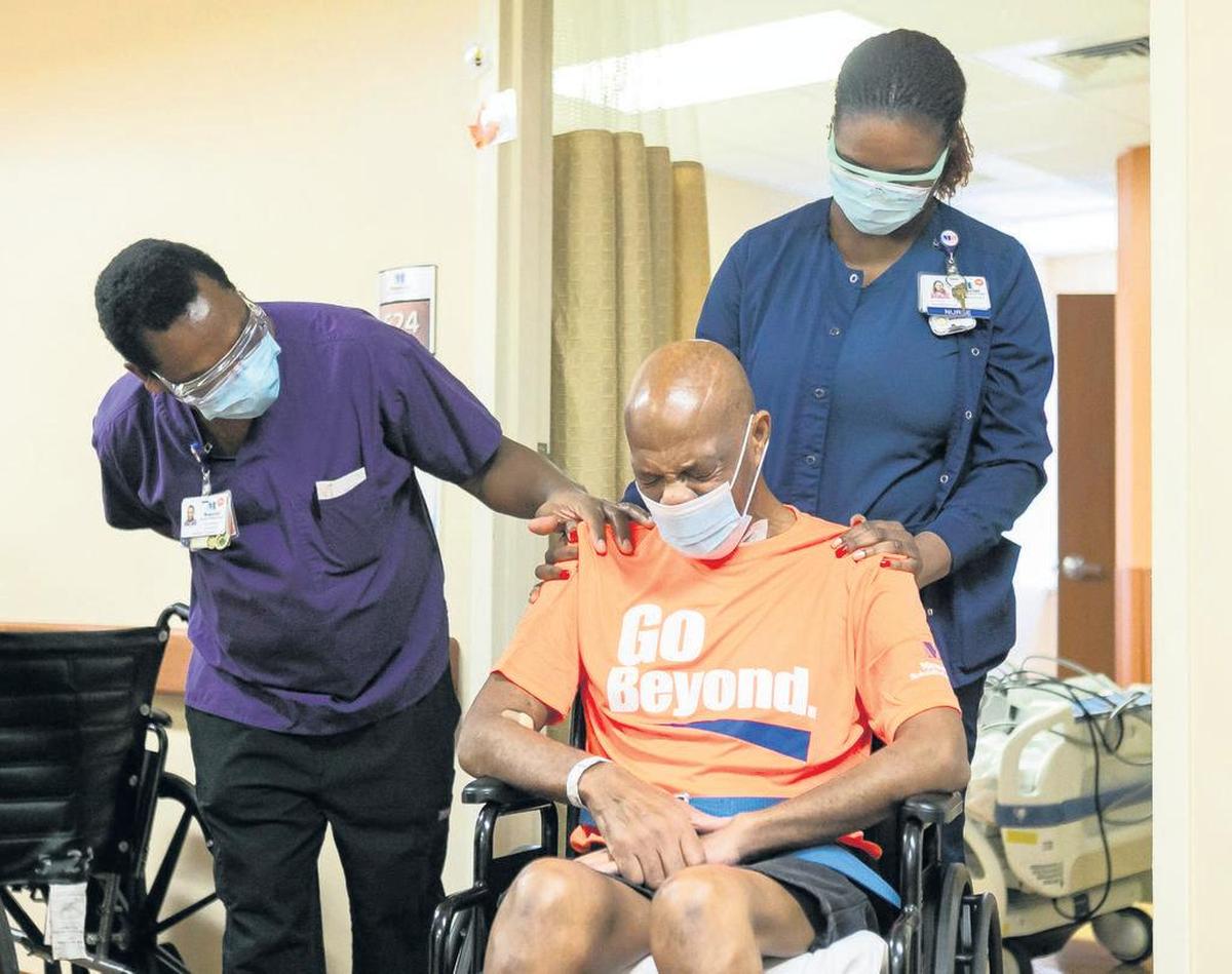 Recovered COVID-19 patient Warren Graham reacts after being released from Memorial Regional Hospital South in Hollywood on Friday, April 16, 2021. Occupational Therapist Samuel Chege, left, helped Graham recover during his two-month battle with the virus.