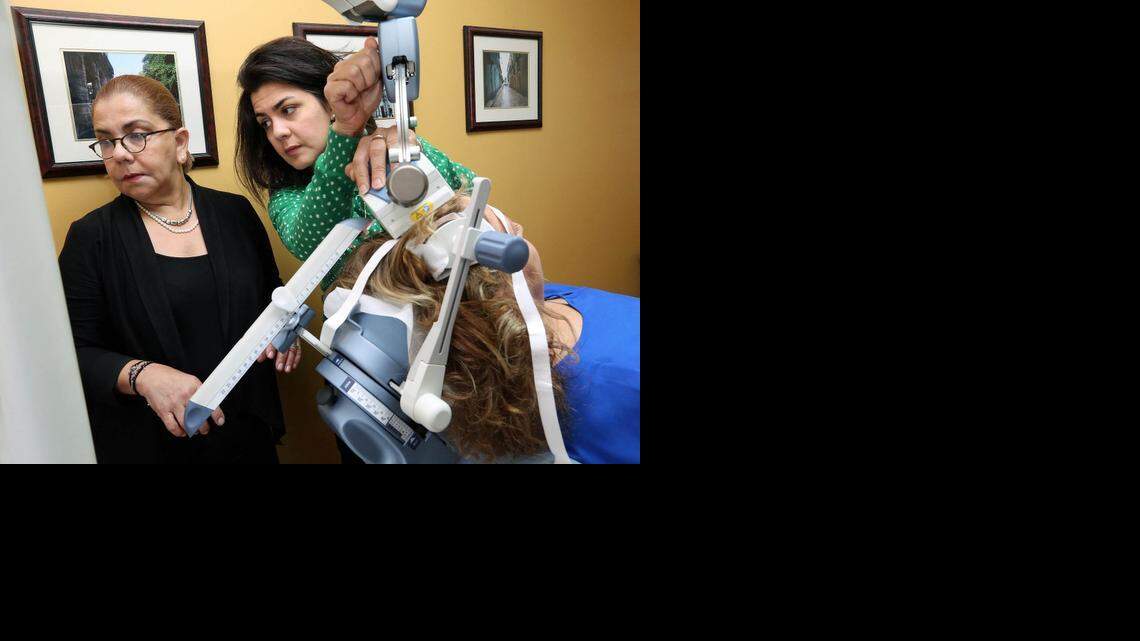 
La Dra. Arocha (izq.) y su asistente Diana Núñez (RN) calibran los impulsos magnéticos para tratar a la paciente.
