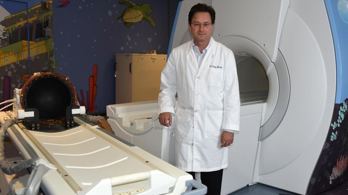 El Dr. Travis Tierney, neurocirujano pediátrico del Hospital Nicklaus Children junto a la máquina de ultrasonido para tratar tumores intracraneales benignos en niños y jóvenes adultos.