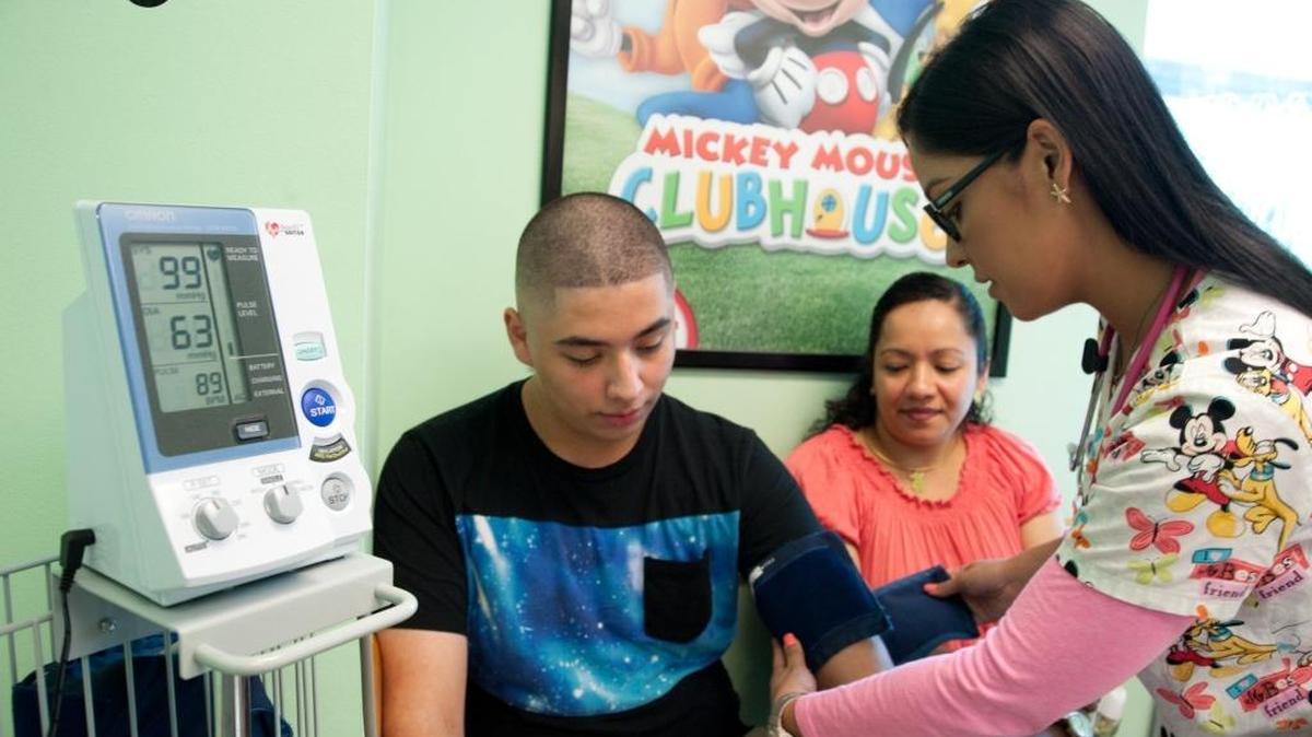 Gisselle Nogueira, (dcha) asistente médico de Nicklaus Children's Hospital, le toma la presión a José Amaya, de 14 años. Amaya participa de un programa de control de peso en el Dpto. de Gastroenterología del hospital.