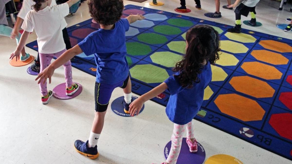 Los niños de Scheck Hillel Community School asumen la asana del guerrero.