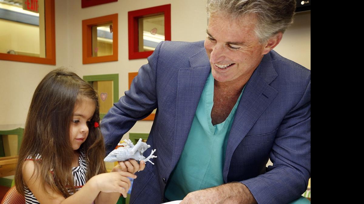 
La pequeña Mia González examina un modelo 3D de su corazón que le entregaron los médicos de Nicklaus Children’s Hospital. En la foto, junto al Dr. Redmond Burke, director de la División de Cirugía Cardiovascular de esa institución. 
