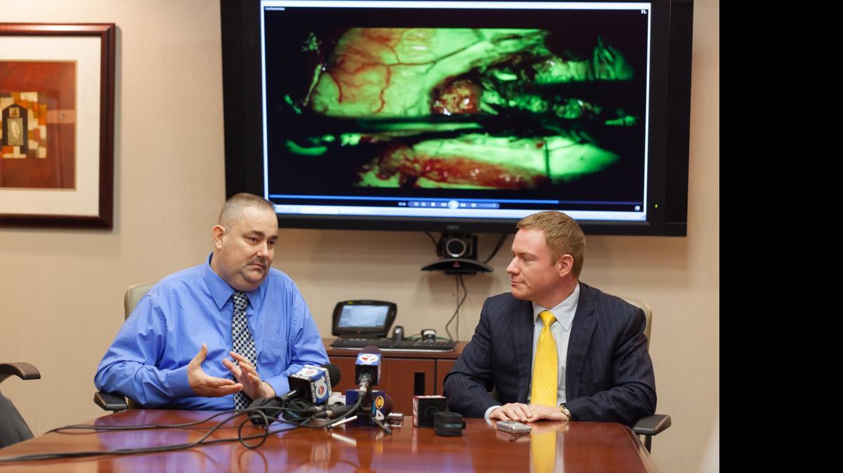 
Shawn Monti (izq.), habla sobre la cirugía del cerebro con el Dr. Ricardo Komotar. Al fondo en la pantalla puede observarse un video de la operación. El Dr. Kotomar es neurólogo y co director de cirugía neuro oncológica en el Sylvester Comprehensive Cancer Center de la Universidad de Miami.
